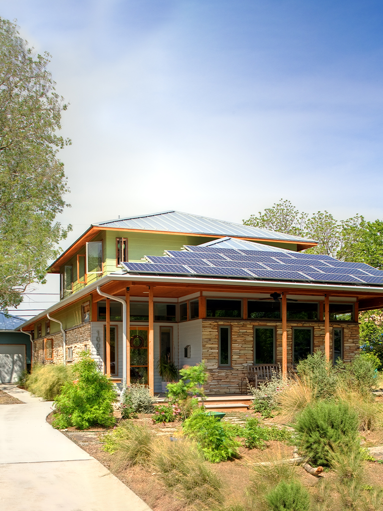 Two-story home with stone and wood siding, solar panels, and native drought-tolerant landscaping
