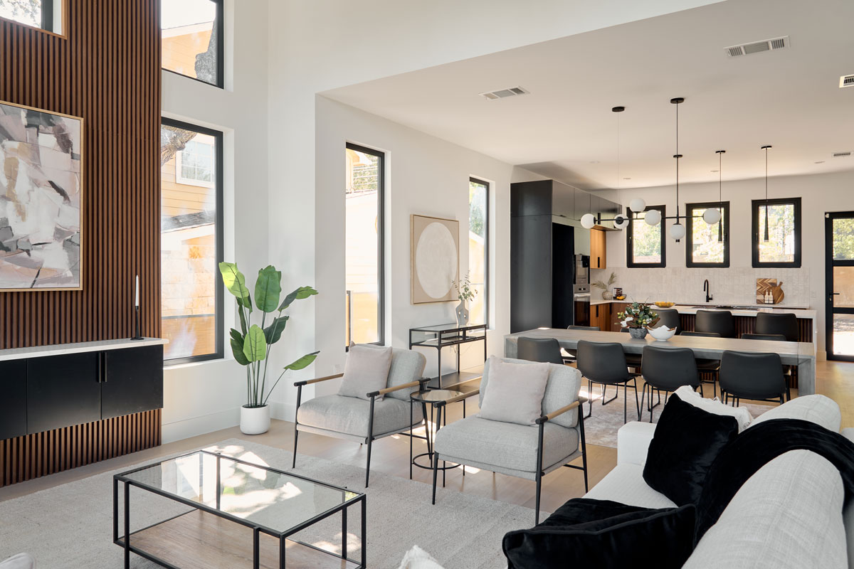 Bright open-plan living room with wood slat accent wall, high ceilings, modern furnishings, and views into the kitchen and dining area