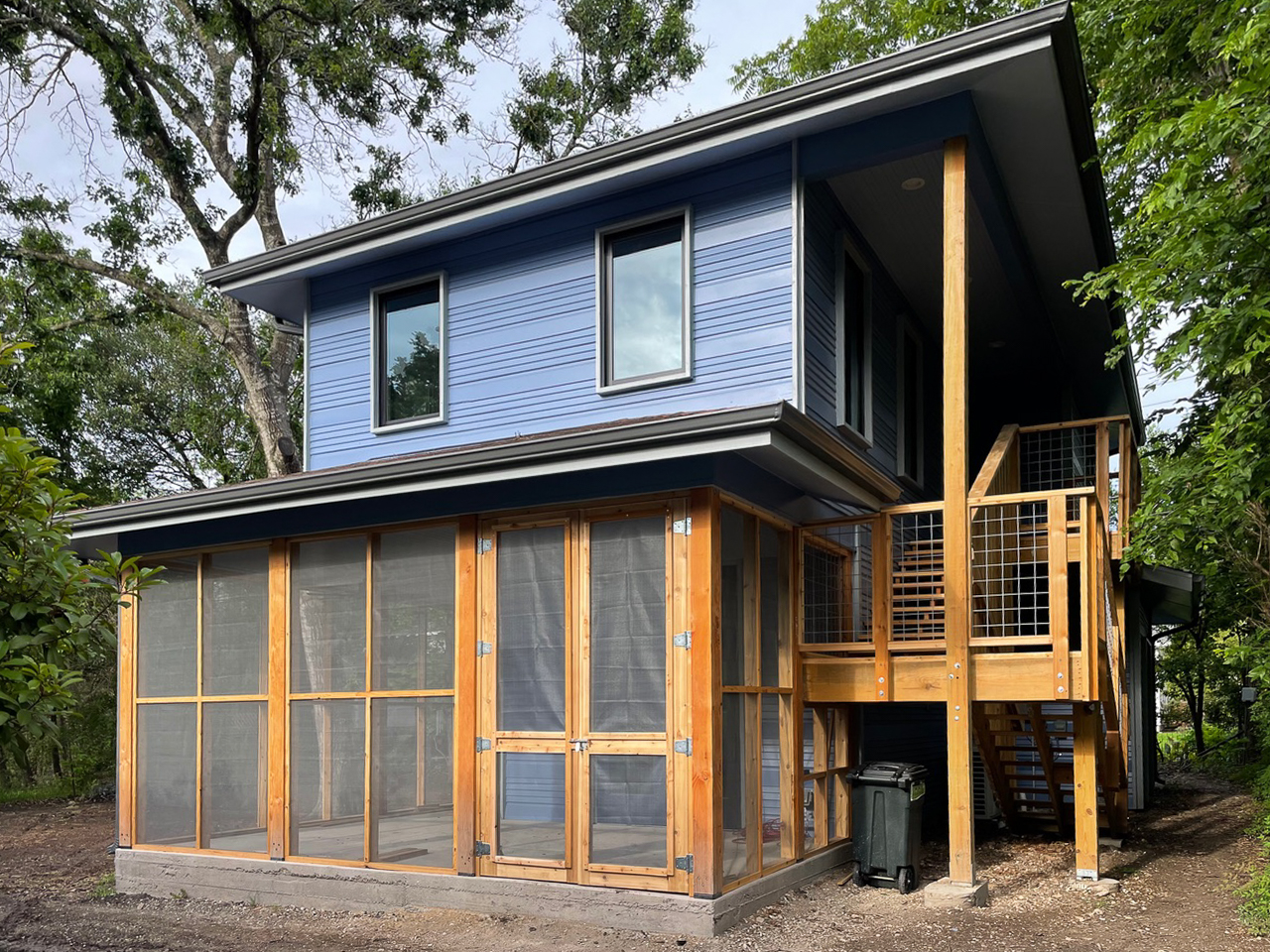 Two-story home with blue lap siding, a cedar-framed screened porch on the ground floor, and an exterior wood staircase leading to a second-floor deck