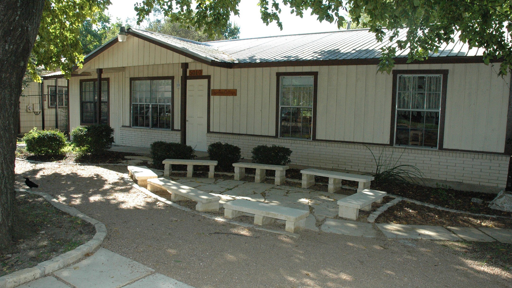 Exterior of renovated school building with stone benches and landscaped courtyard, Austin Montessori School campus expansion, Austin TX
