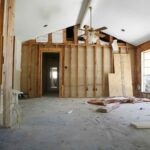aInterior under construction with exposed wood stud framing, a vaulted ceiling, and a bare concrete floor