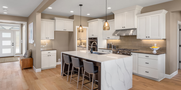 Remodeled kitchen with white shaker cabinetry, marble waterfall island, pendant lighting, and hardwood floors in an Austin home