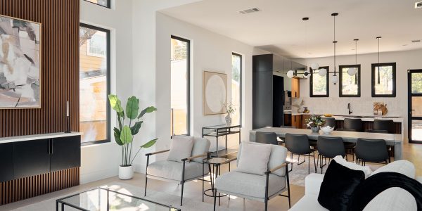 Bright open-plan living room with wood slat accent wall, high ceilings, modern furnishings, and views into the kitchen and dining area