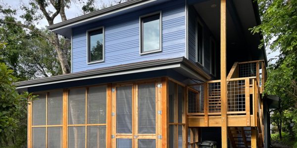 Two-story home with blue lap siding, a cedar-framed screened porch on the ground floor, and an exterior wood staircase leading to a second-floor deck