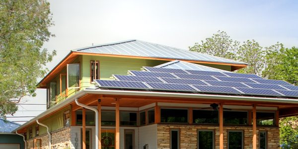Two-story home with stone and wood siding, solar panels, and native drought-tolerant landscaping